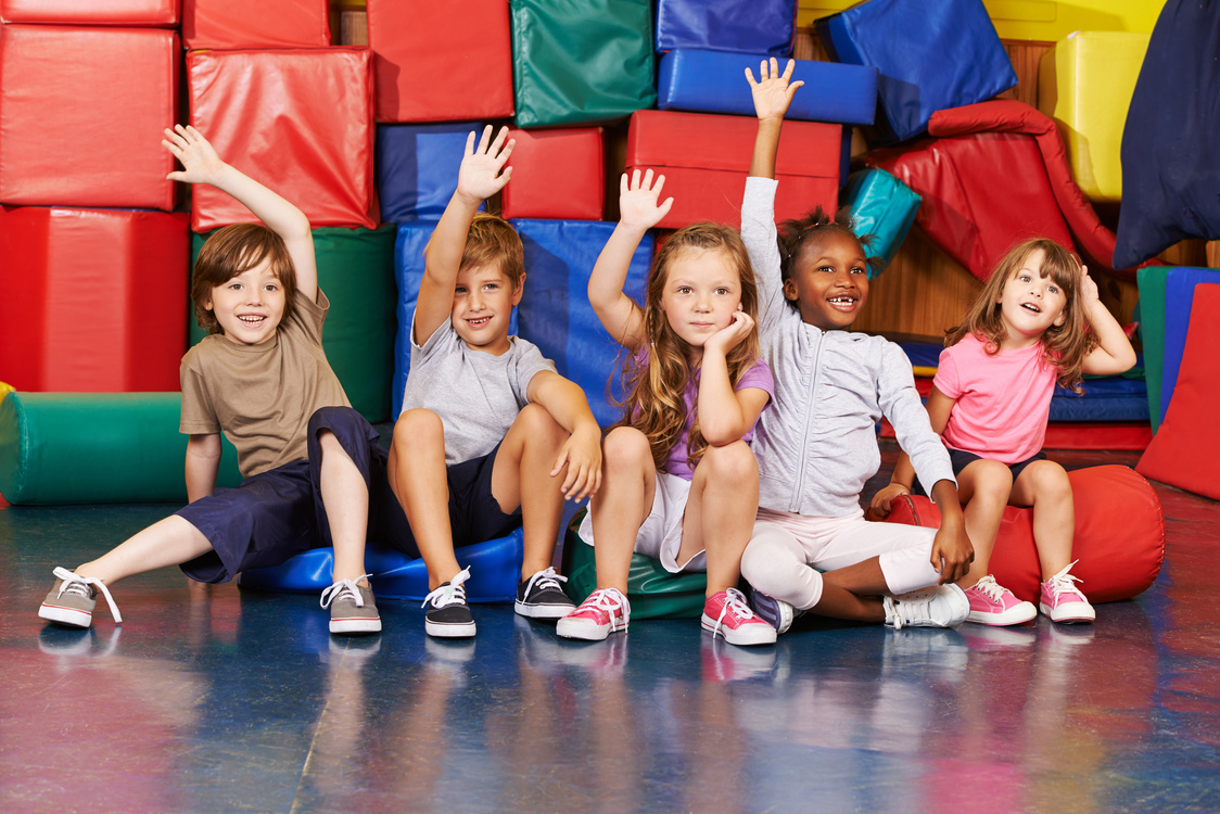 Children Raising Their Hands in Gym of School